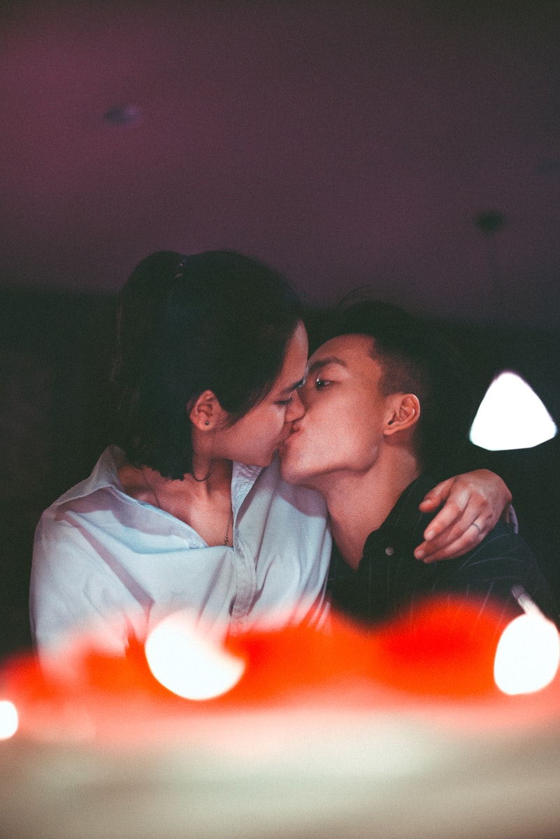 Man and Woman Kissing Near Pendant Lamp