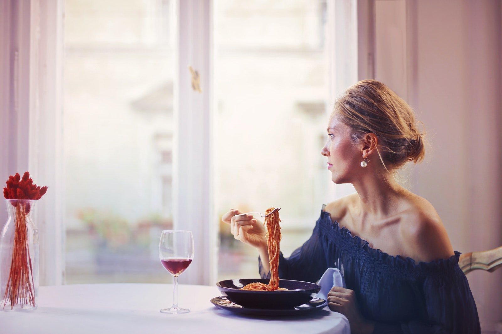 Woman Sitting on Chair While Eating Pasta Dish