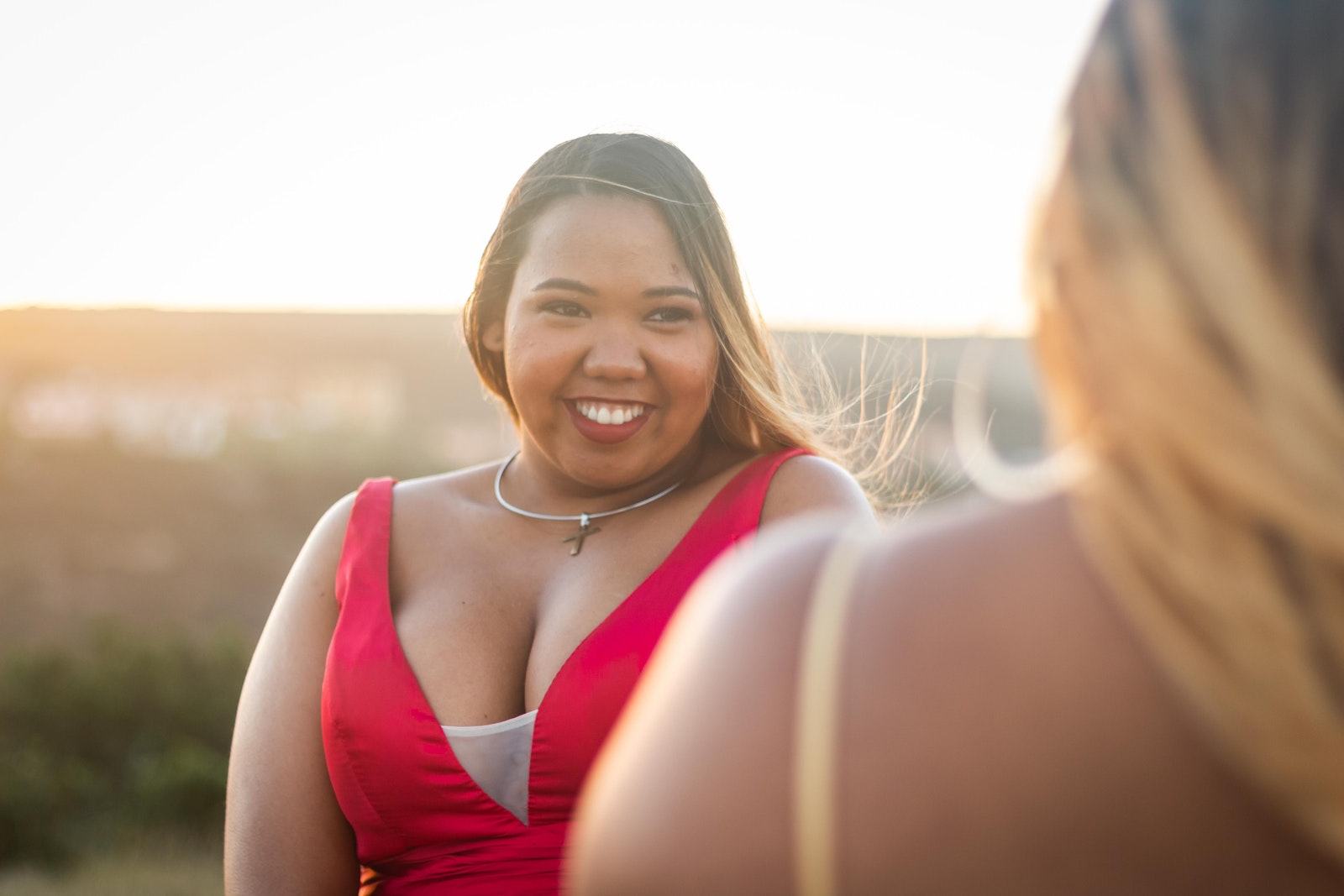 Happy stylish black woman with unrecognizable girlfriend on street