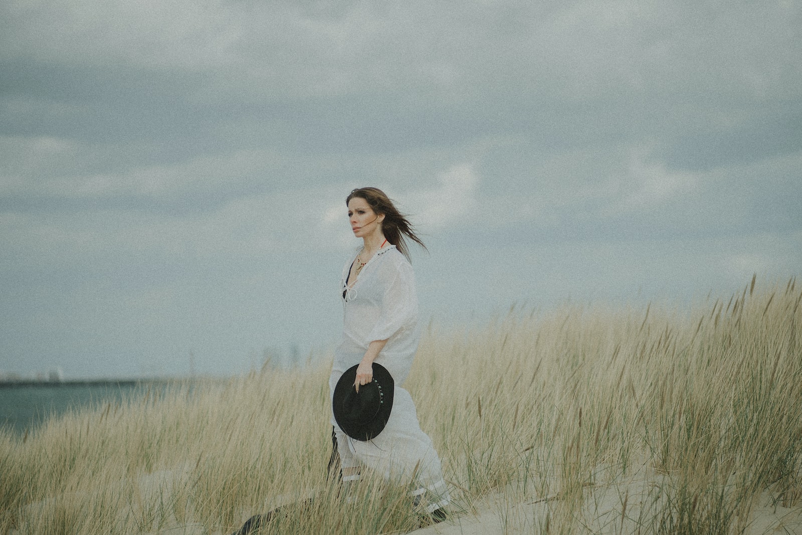 woman in white long sleeve shirt and black pants standing on green grass field under gray