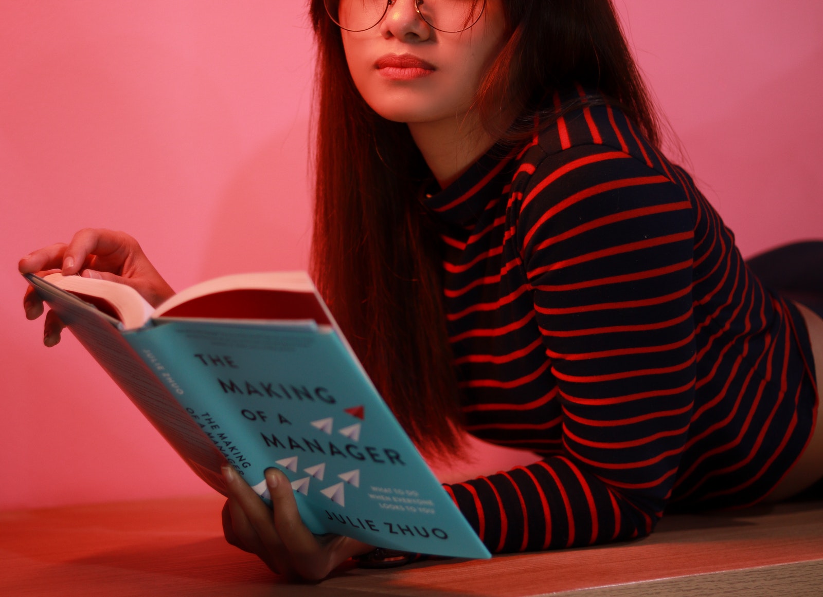 Woman in Red and Black Striped Long Sleeve Shirt Holding Blue Book