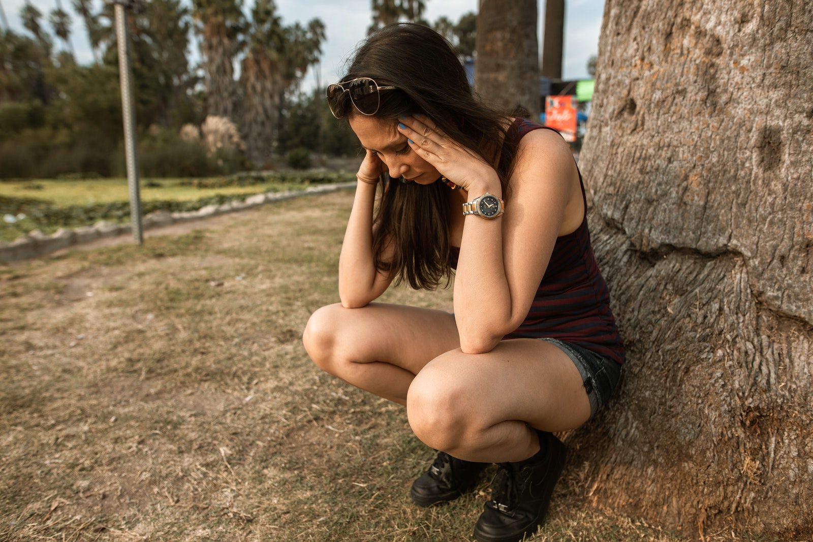 Woman in Black Tank Top and Black Shorts Sitting on Brown Rock