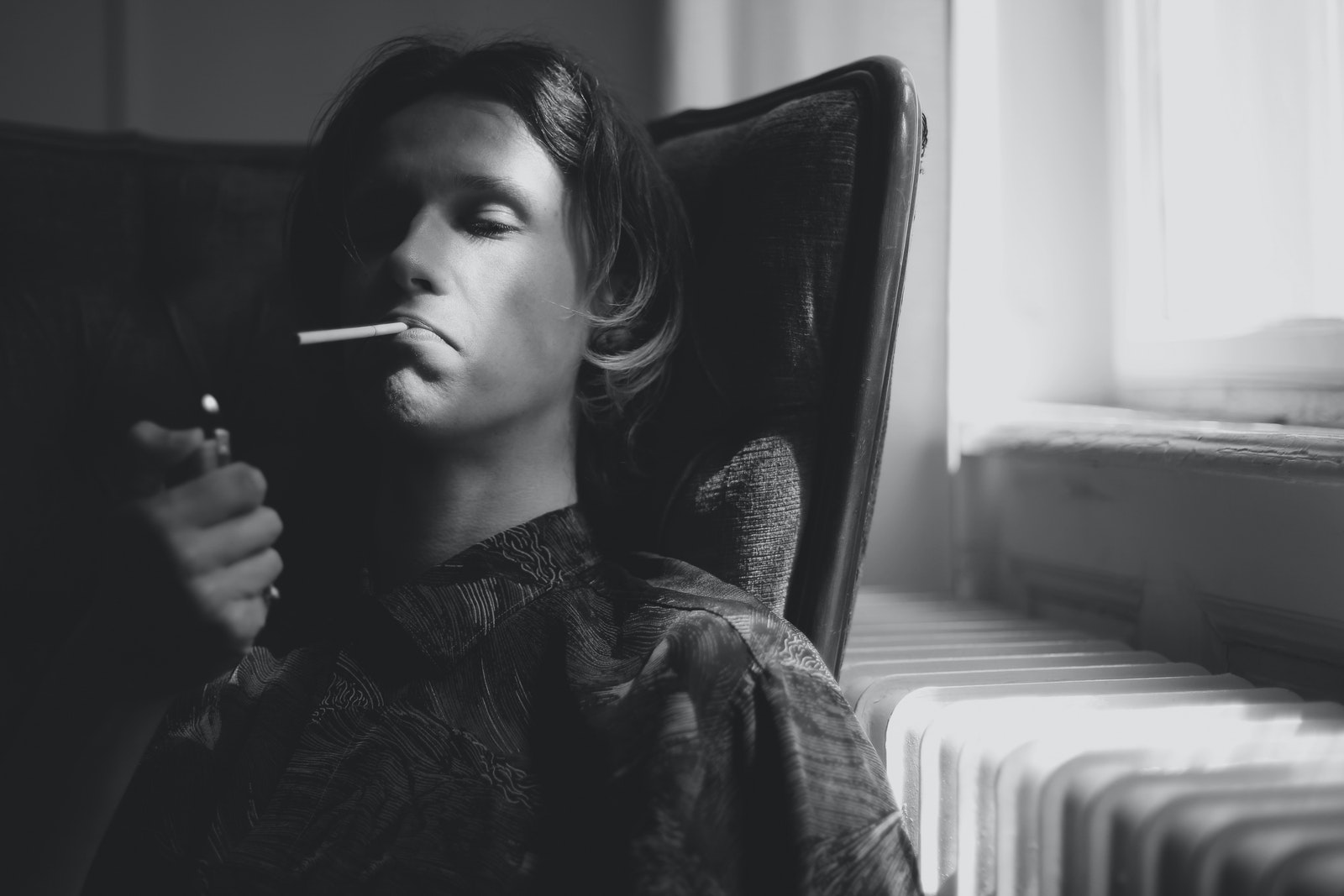 Thoughtful man lighting cigarette in room