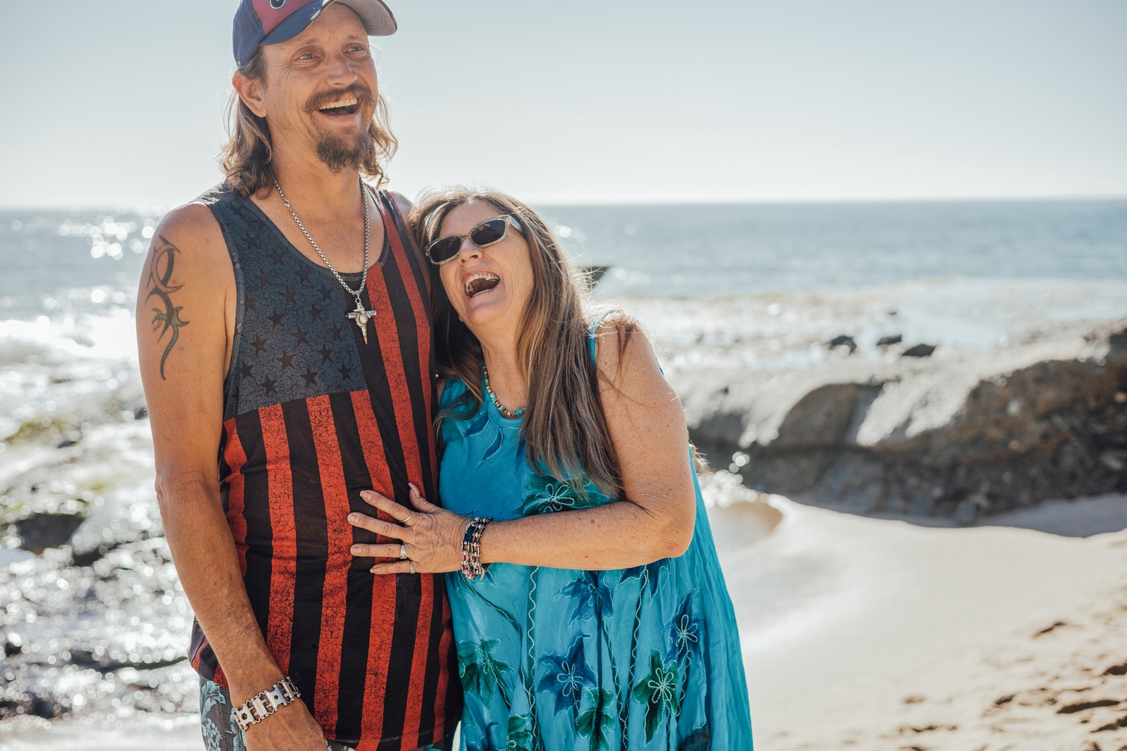 2 Women in Blue and Red Tank Top and Blue Cap Standing on Beach