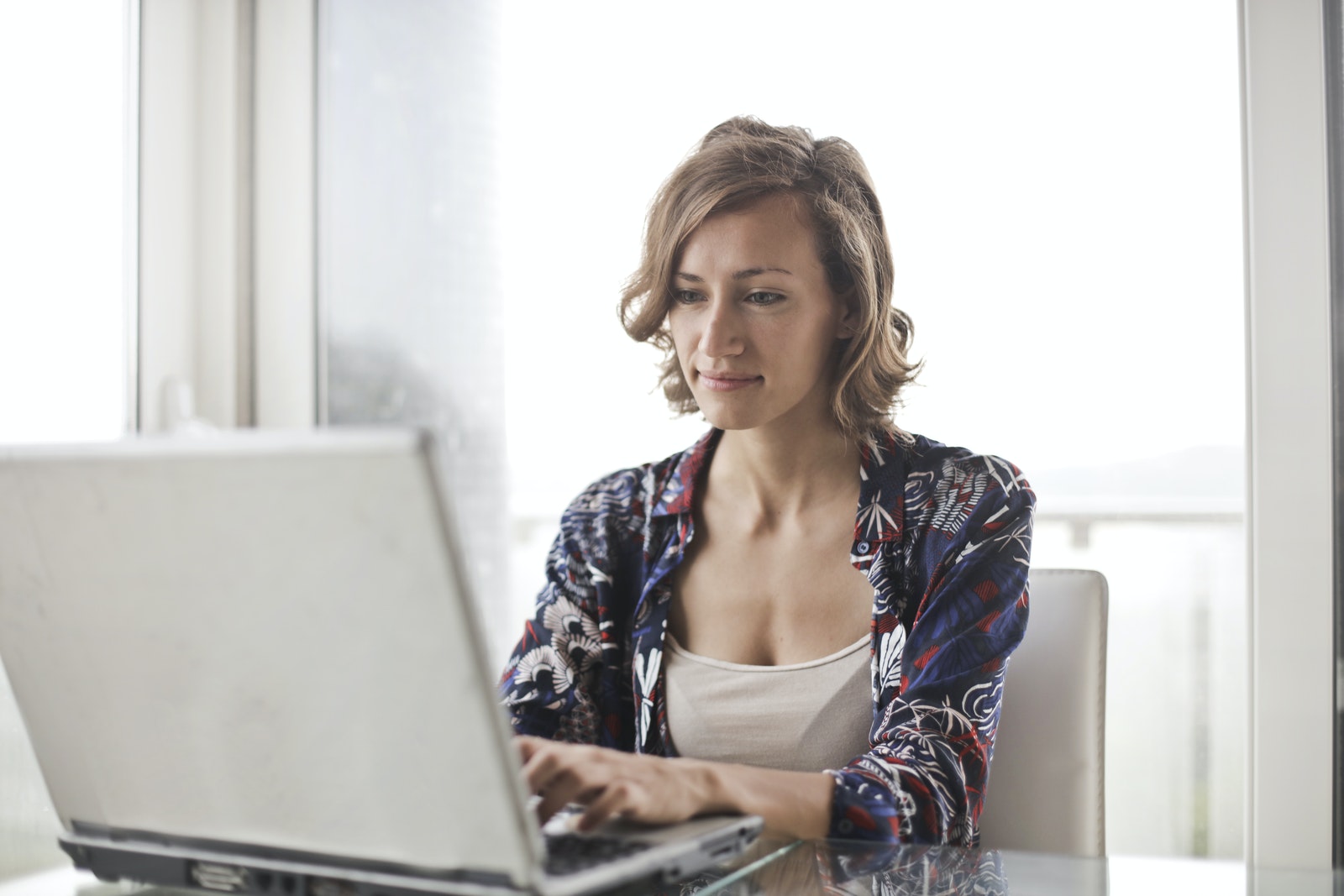 Woman in Blue Floral Top Sitting While Using Laptop