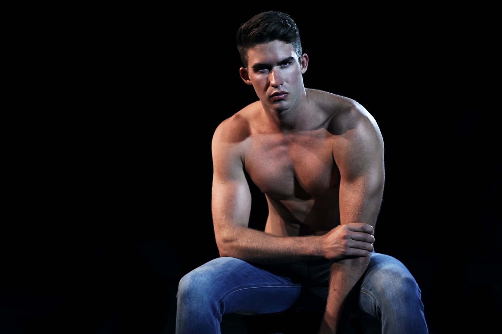 topless man wearing blue denim jeans sitting