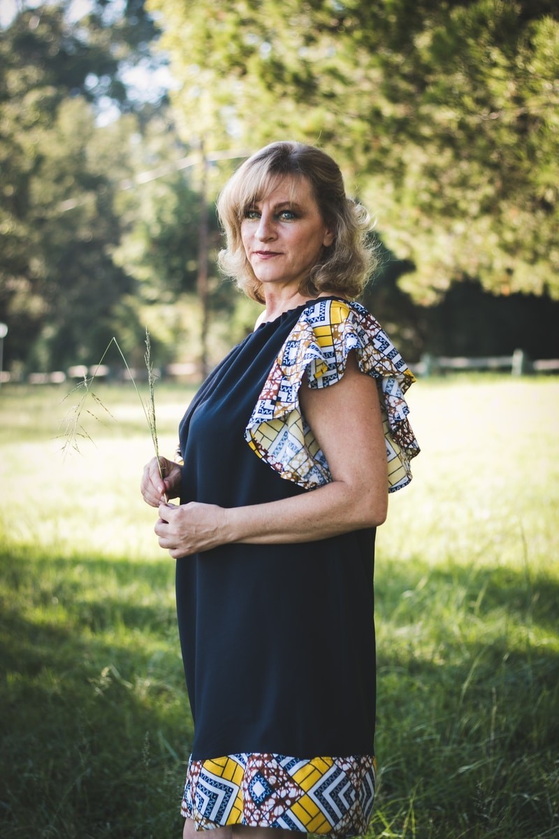 woman holding green plant standing near trees