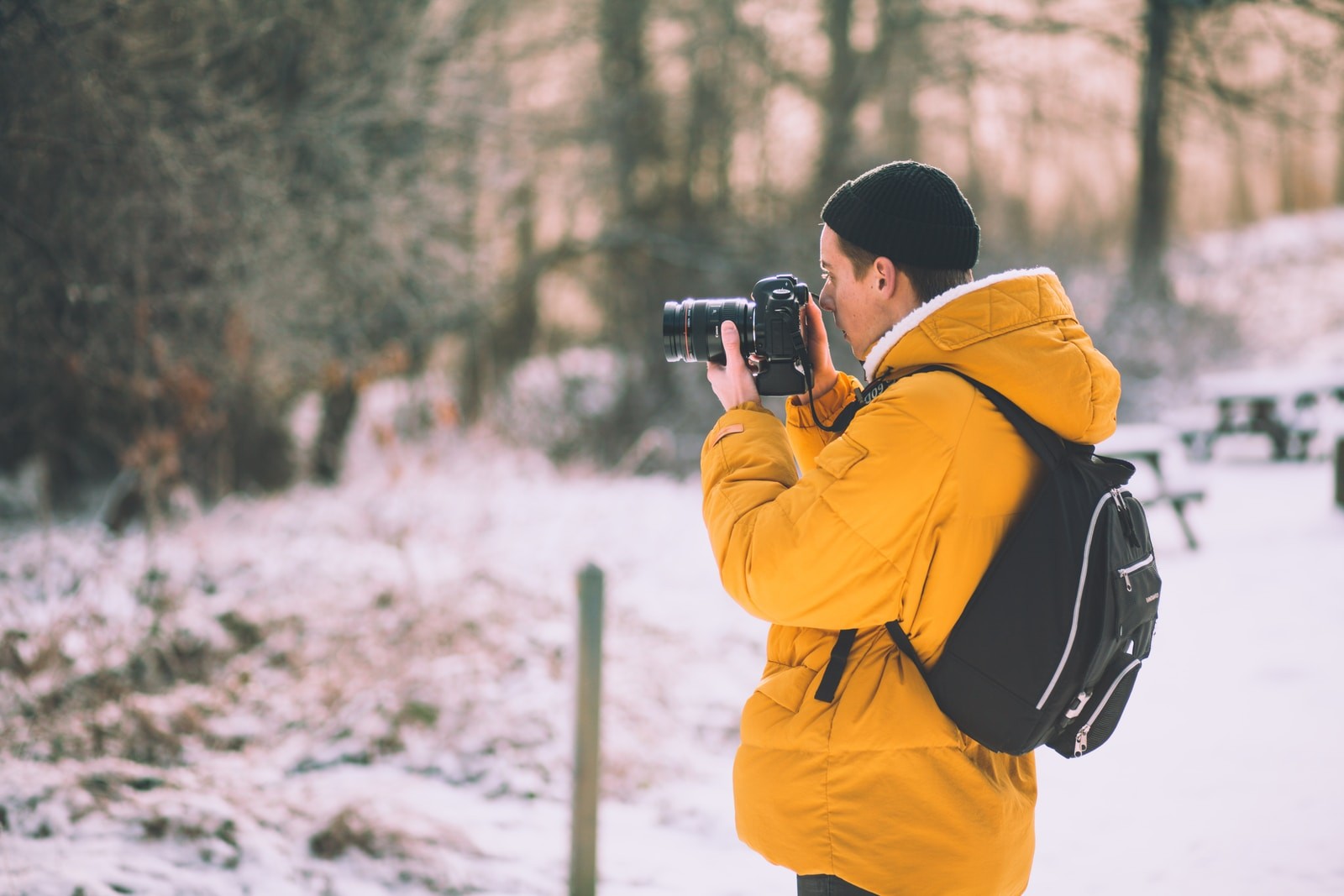 man wearing brown pull-over jacket using black camera